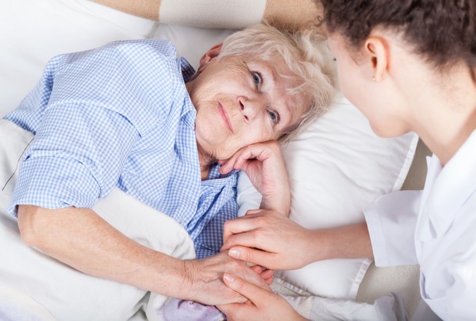 A hospice social worker holds the hand of a hospice patient.