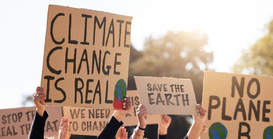 Protesters hold up signs reading “Climate change is real” and “Save the Earth.”