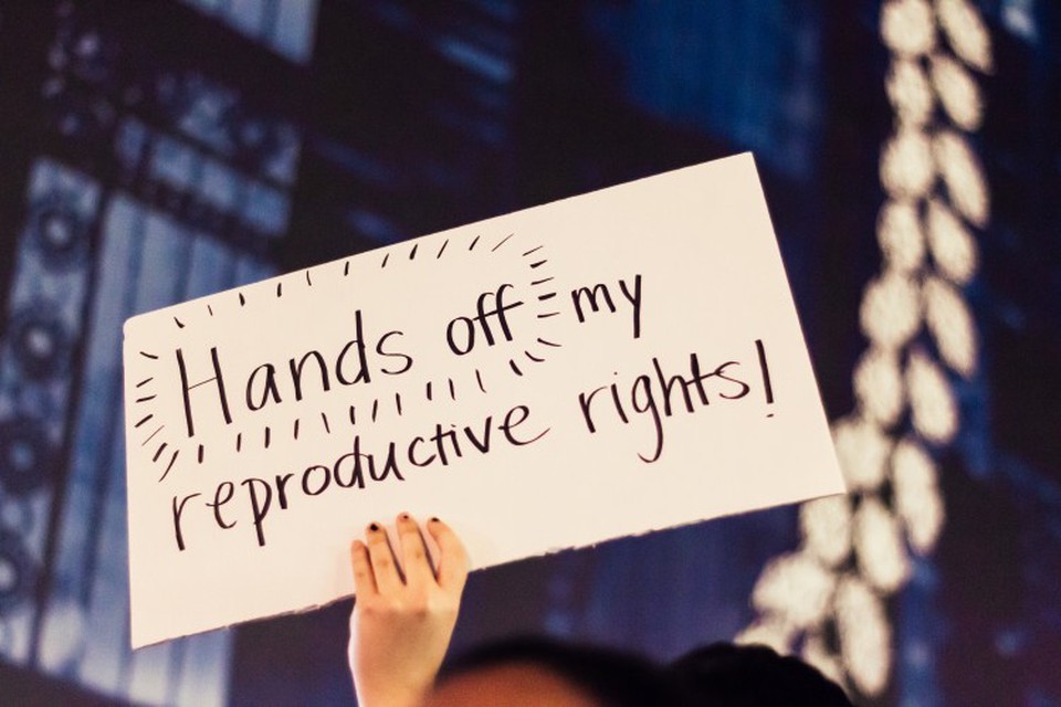 A person holds up a sign that reads “Hands off my reproductive rights!”