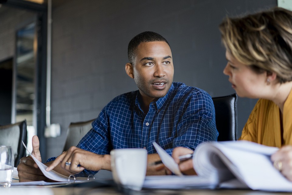 Man and woman talking over coffee and paperwork