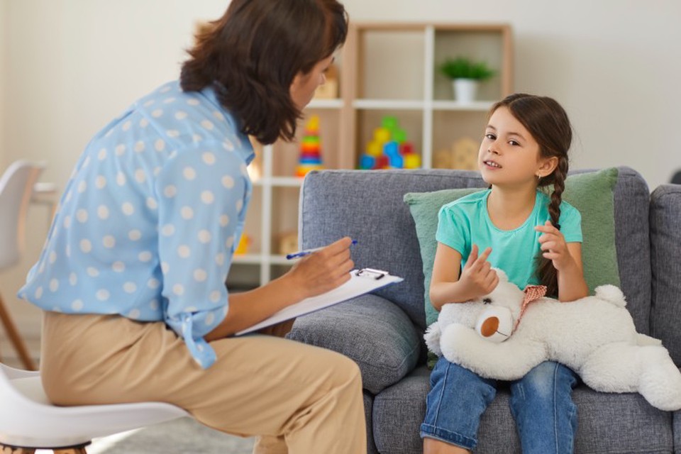 A social worker takes notes while speaking with a young girl.